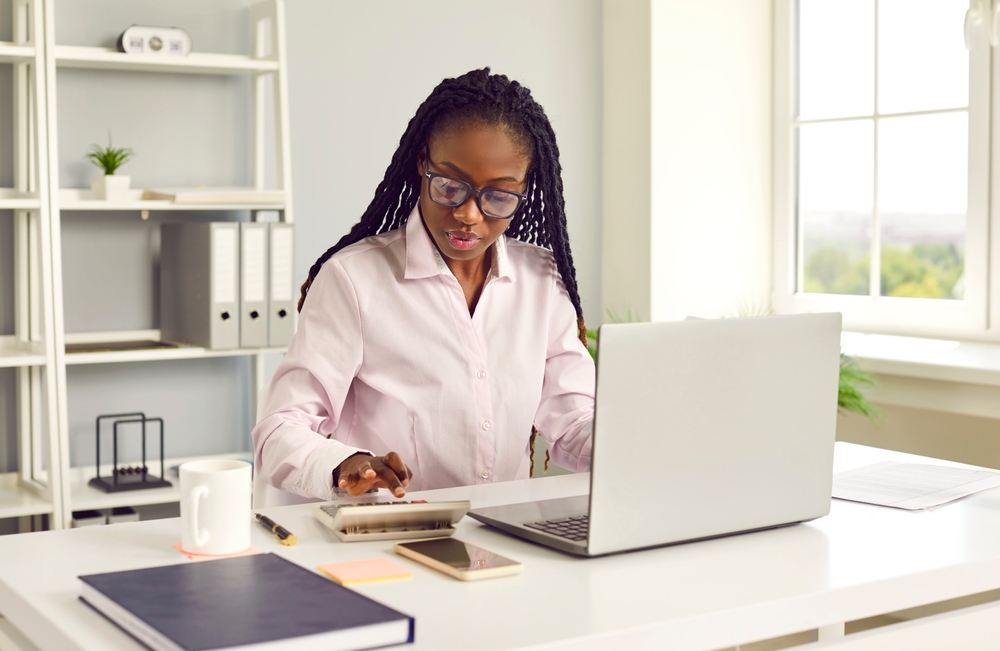 Small business owner calculating company taxes on laptop at desk